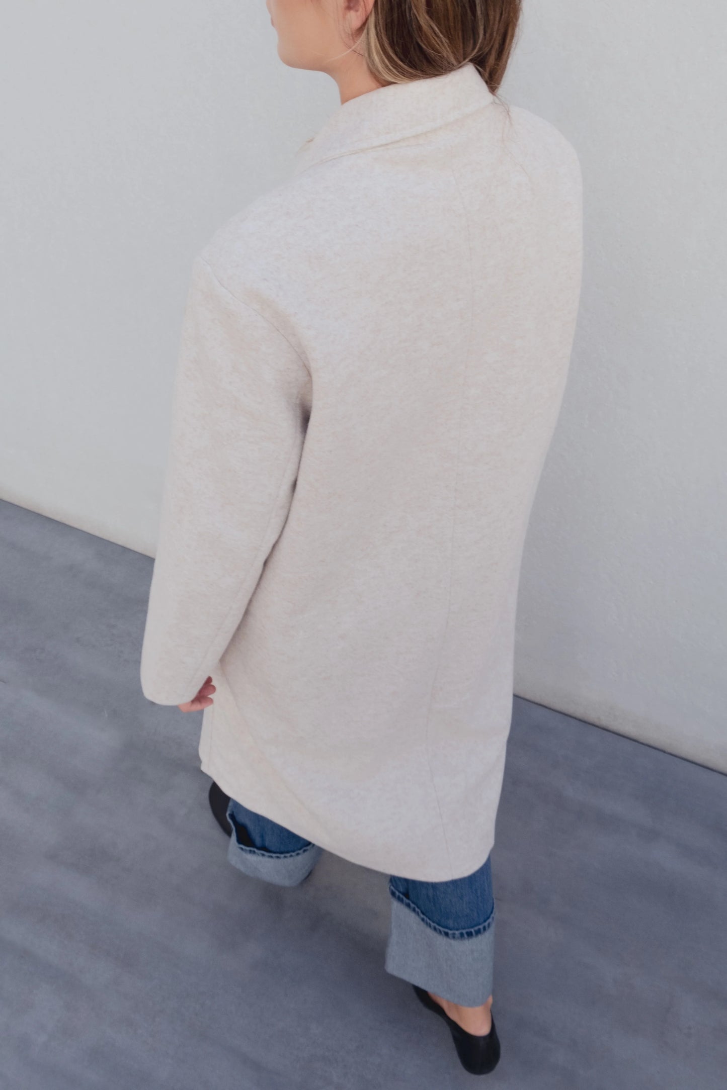 Vista trasera del abrigo cruzado beige con caída recta y hombro relajado, estilo atemporal – Zenda Couture