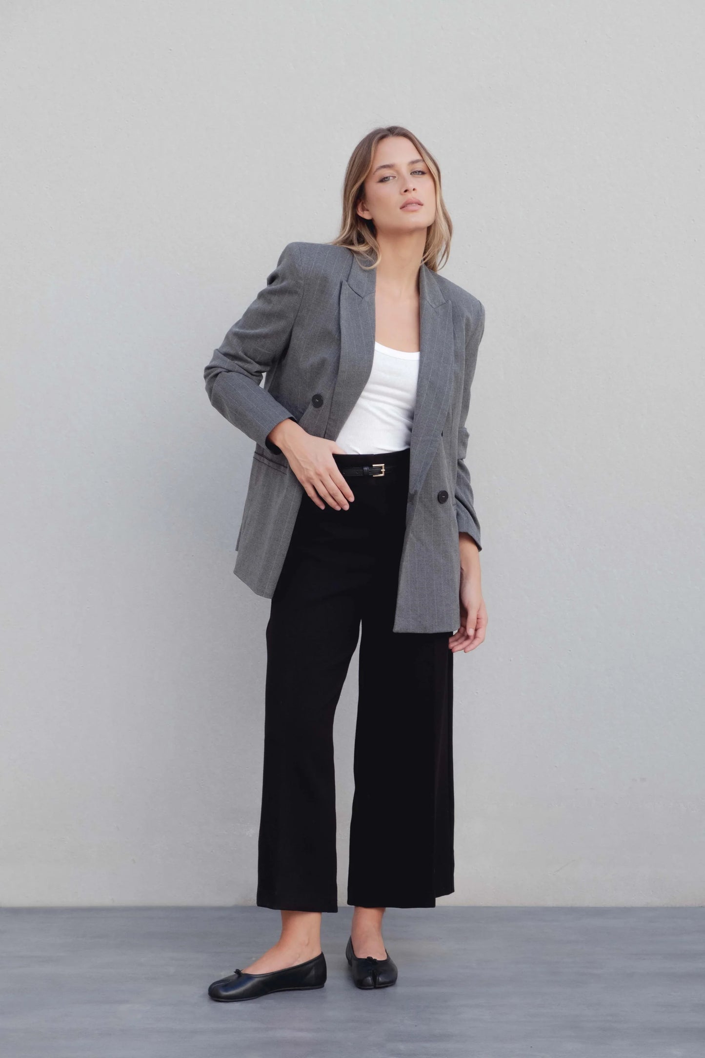 Blazer raya diplomática gris combinado con top blanco y pantalón negro para un look de oficina actual – Zenda Couture