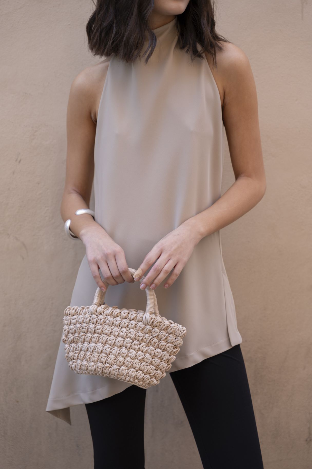 detalle del cuerpo halter nude y bolso de rafia beige