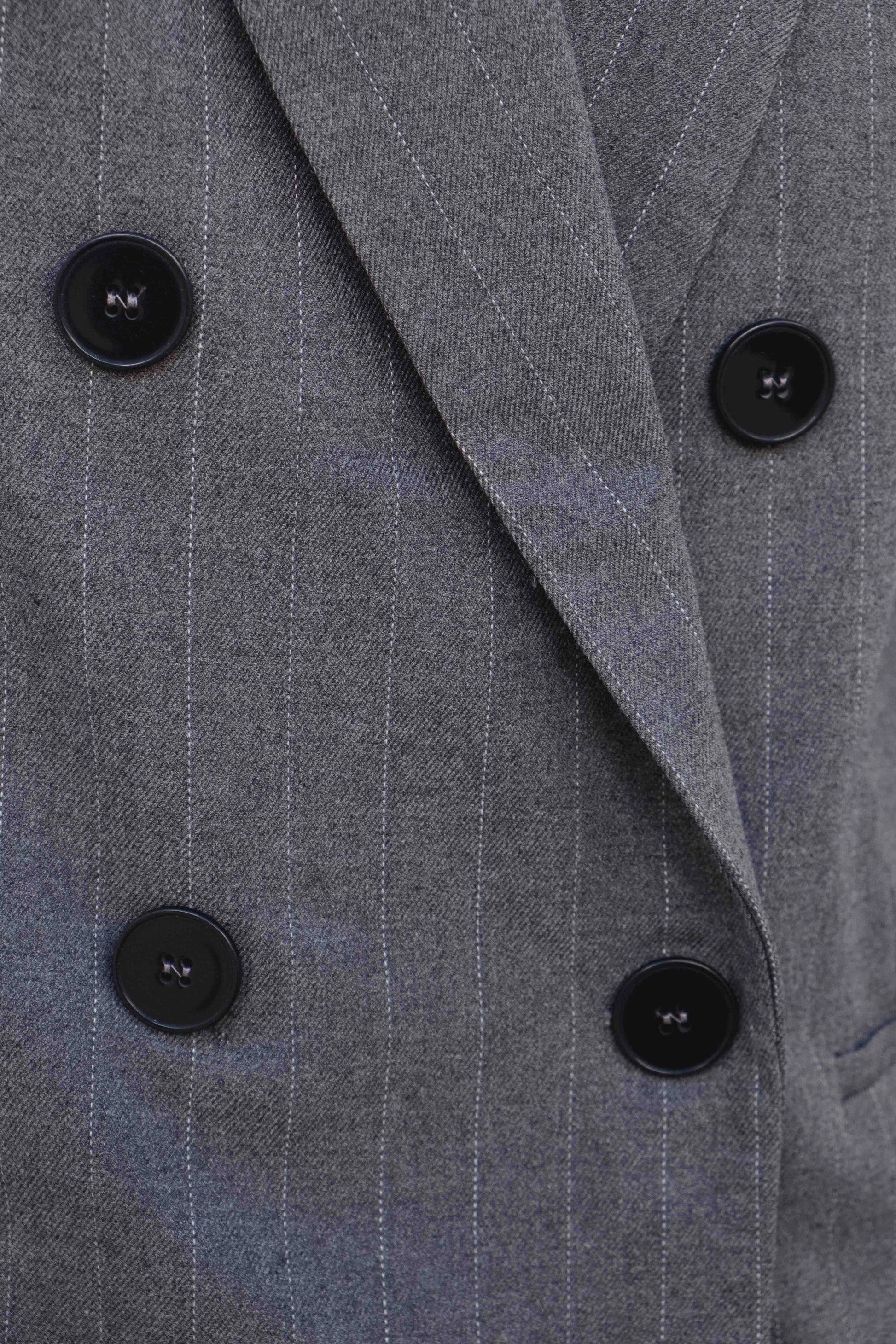 Primer plano de doble botonadura y solapa en blazer raya diplomática gris, acabado sastre – Zenda Couture